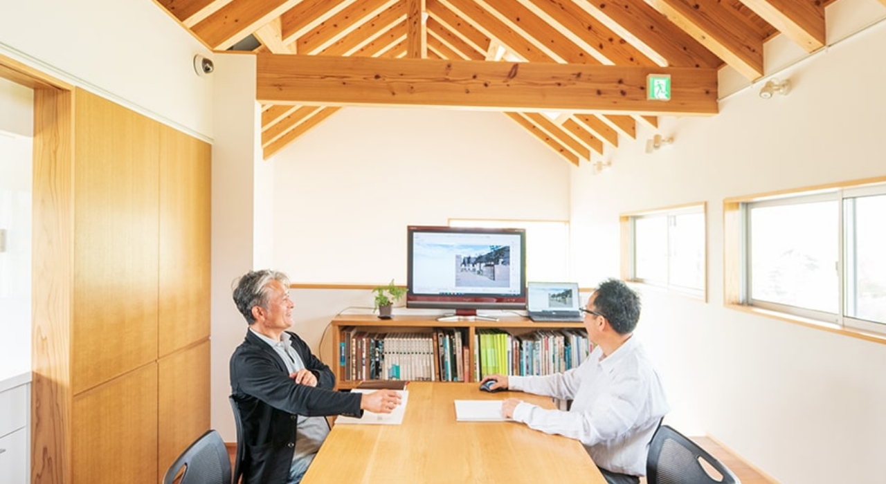 木造住宅の中、二人の男性が談笑しています